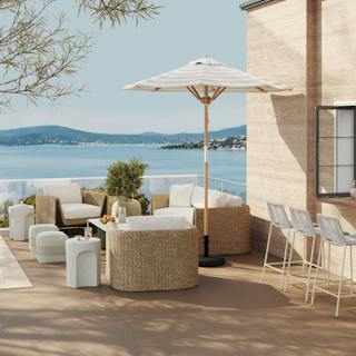 A stylish patio with black wicker chairs, a sofa, and a large umbrella.