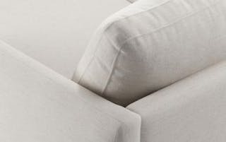 Close-up of an ivory fabric sofa arm with a plush back cushion.