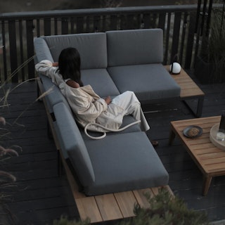Moody patio featuring person sitting on the Kezia 100" Outdoor Modular Sectional - Whale Gray