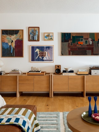 Modern living room with a wood sideboard, gallery wall, and cozy decor accents.