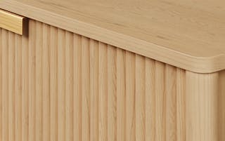 Close view of wood grain, fluted panels, and brass handles on Liv's cabinet panels