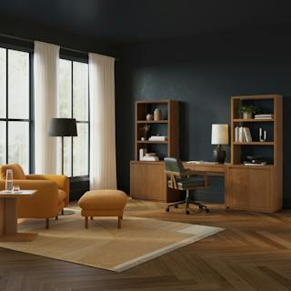 A modern home office with a wooden table, mixed chairs, and natural lighting.