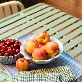 Bowls of cherries and peaches, atop the Sarek Dining Table in Khaki Green. Photo by @cupofjo