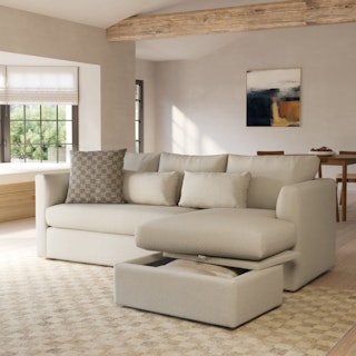 A light beige sectional sofa with a reversible storage chaise in a bright living room.