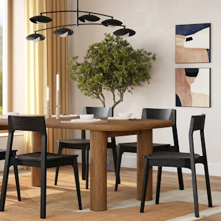 A modern dining room with a wooden table, mixed chairs, and bold lighting.