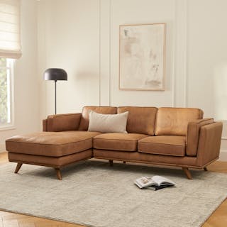 A brown leather sectional sofa with a left chaise in a cozy living room.