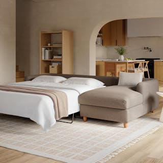 A brown sleeper right sectional sofa converted into a bed in a living room.