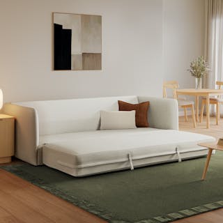 An ivory fabric sofa bed opened up in a living room.