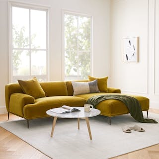 A white right sectional sofa with pillows in a light, minimal living room.