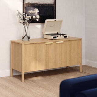 Liv 48" Media Unit in White Oak provides storage behind fluted closed doors, displaying flowers and a record player