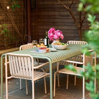 Styled image of the Sarek 67" Outdoor Dining Table in Khaki Green with Sarek Stackable Armchairs in Taupe. Photo by @cupofjo